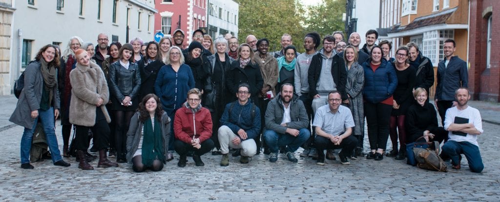 Group of people stand outside smiling at camera.