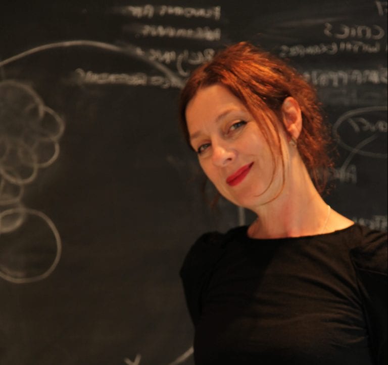 Jane Grant stands in front of blackboard.