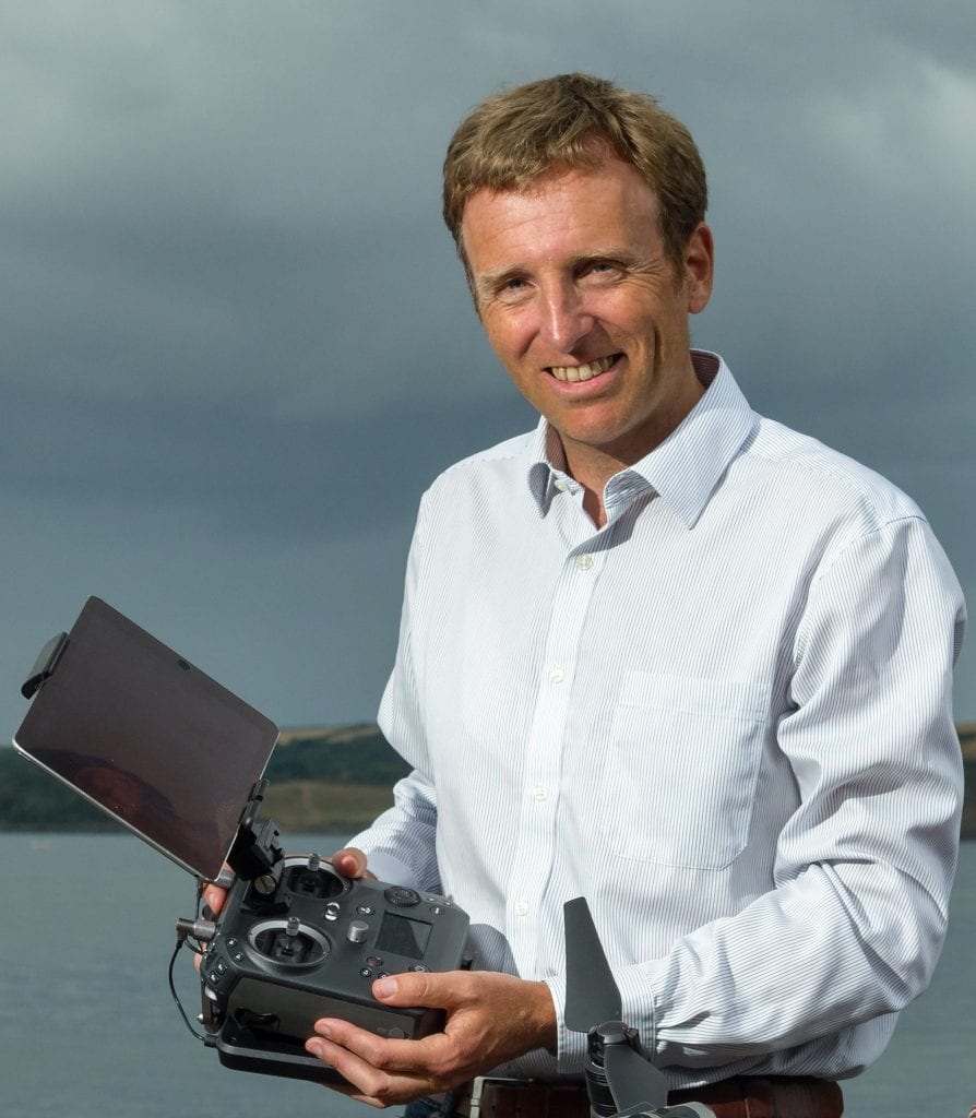 Lloyd Brina holding a remote control with tablet attached.