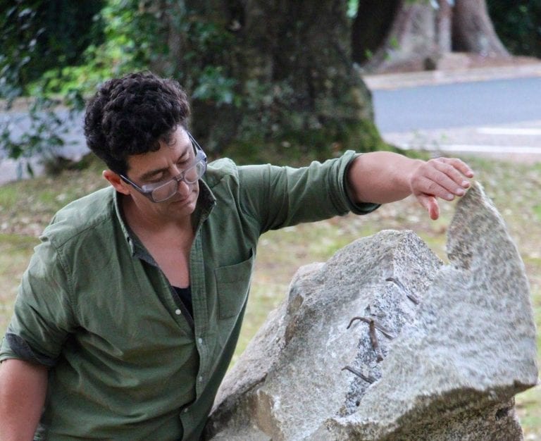 Man in glasses looks at rock spit in half.