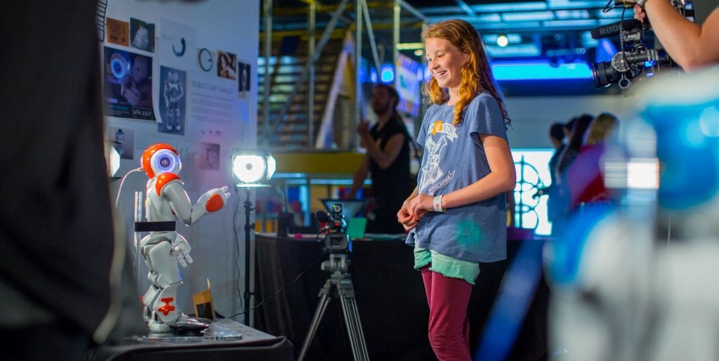 Girl smiles at robot at Puppet Presence.