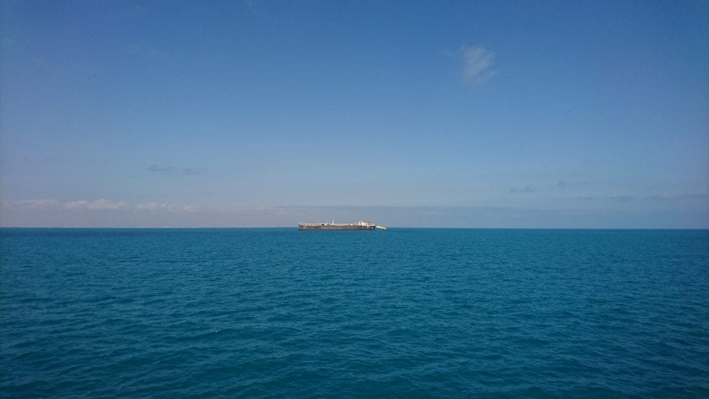 Wide blue ocean with long boat in distance.