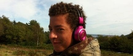 Man wearing pink headphones standing outdoors.