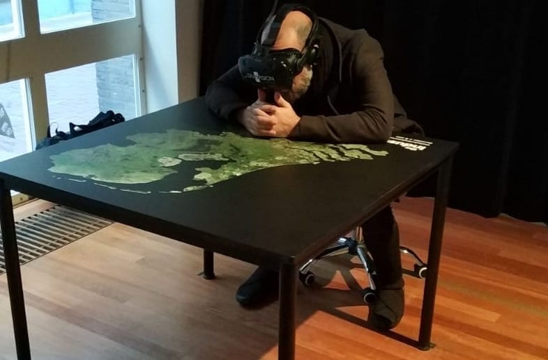 Man wearing VR headset looks at table of Netherlands with map on.