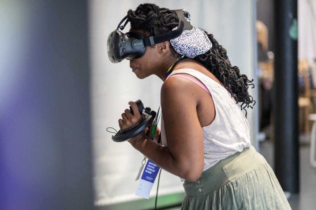 Woman wearing VR headset and holding remote at SWCTN Showcase.