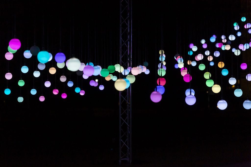 Strings of multicoloured lights hang from ceiling at AudioWave Squidsoup installation.