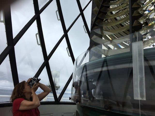 Woman uses camera to look up at object in front of her.