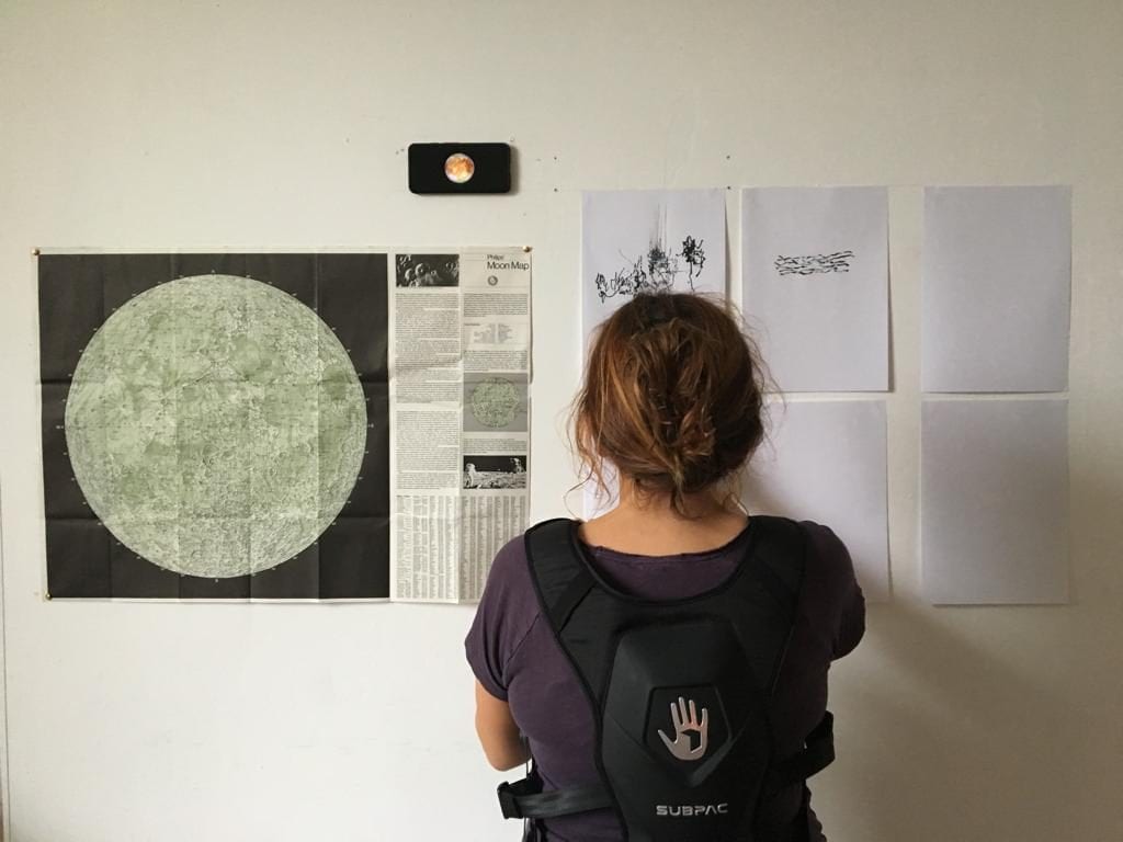 Woman looks at pieces of paper attached to wall.