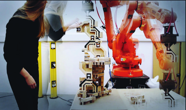 Woman works on machine with robotic arm in background.