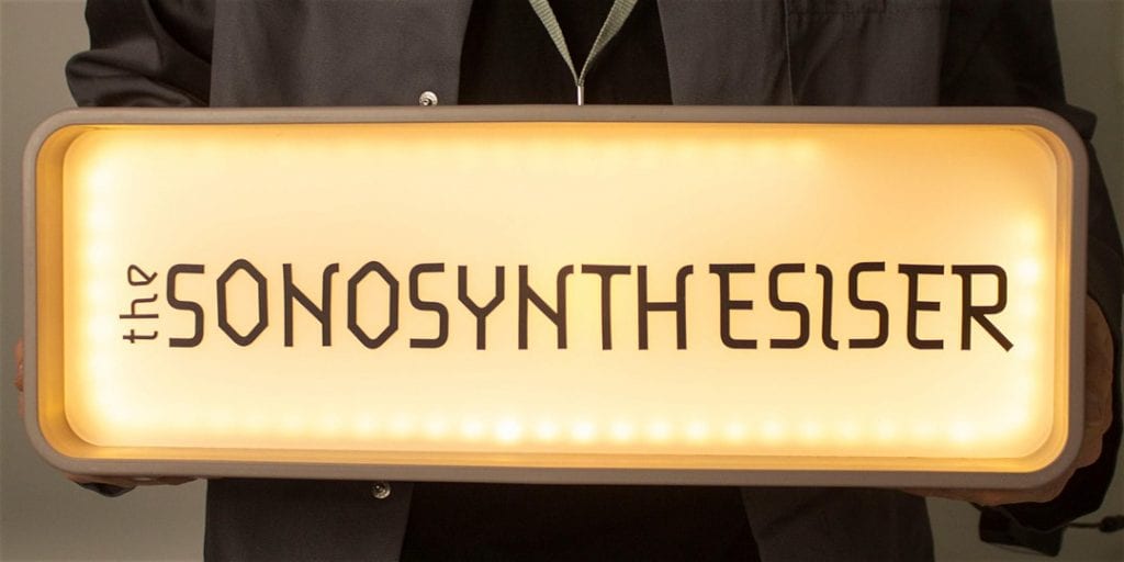 Someone holds lightbox reading "The Sonosynthesiser."