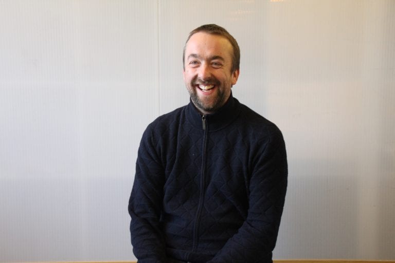 Tomas Millar smiling, wearing a black jumper.