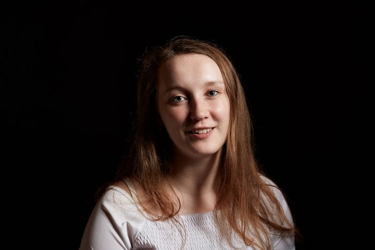 Laura Sobola smiles at camera with dark background.