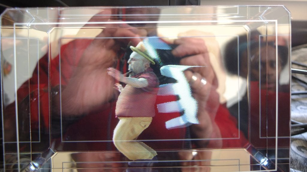 Person taking a photo of a hologram of a man dancing with a pipe in his mouth.