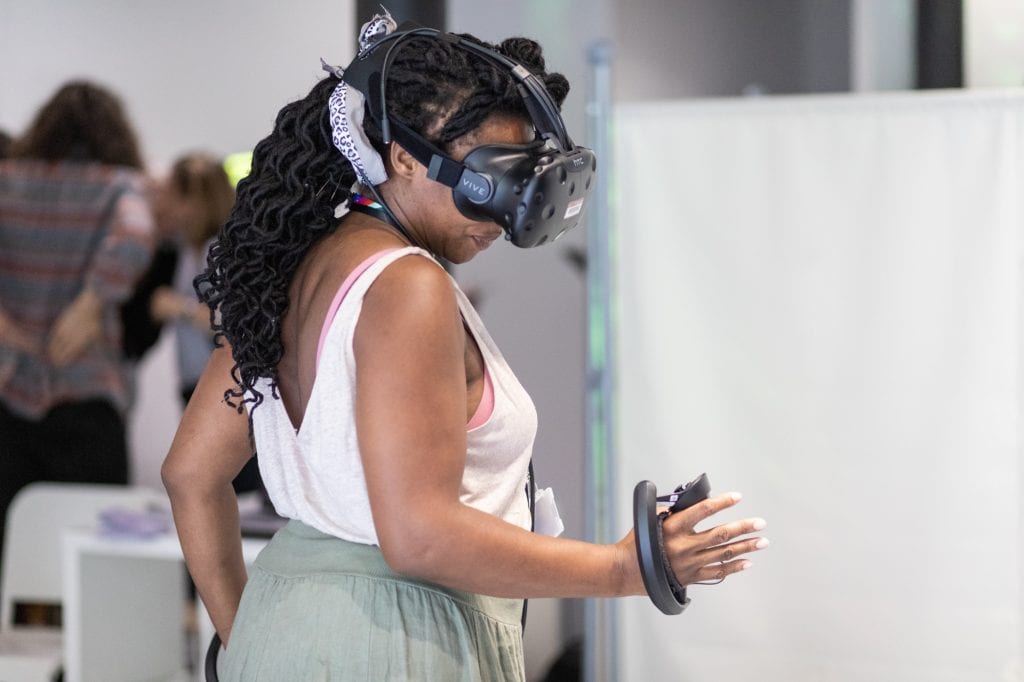 Woman stretches out her hand while wearing VR headset at SWCTN Showcase