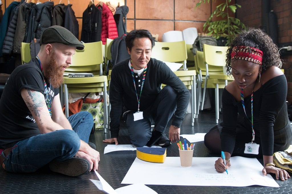 Three creative producers gather on the floor writing on a large piece of paper