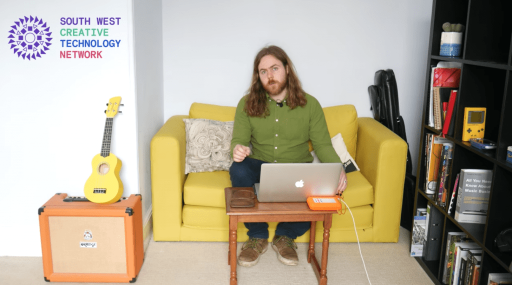 a man with shoulder length hair sits on a yellow sofa