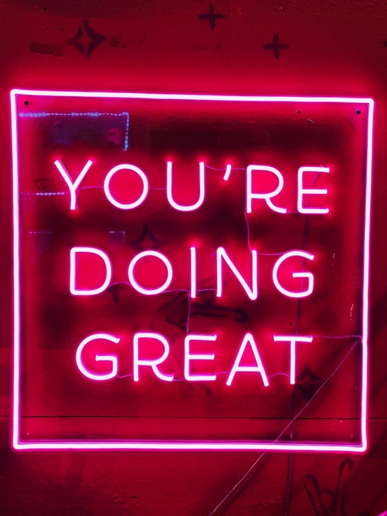 pink neon sign that reads; You're Doing Great