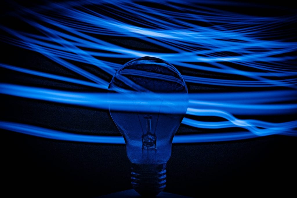 lightbulb surrounded by lines of light blue light. the background is dark blue